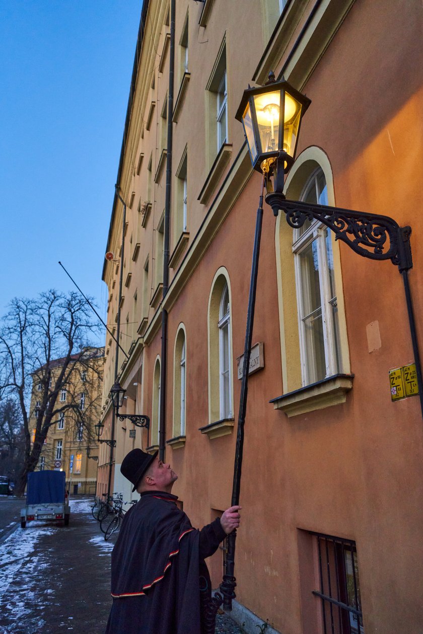 Na zdjęciu widać mężczyznę, który zapala latarnię na Ostrowie Tumskim we Wrocławiu