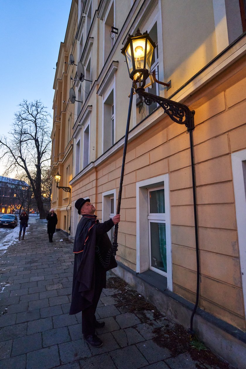 Na zdjęciu widać mężczyznę, który zapala latarnię na Ostrowie Tumskim we Wrocławiu