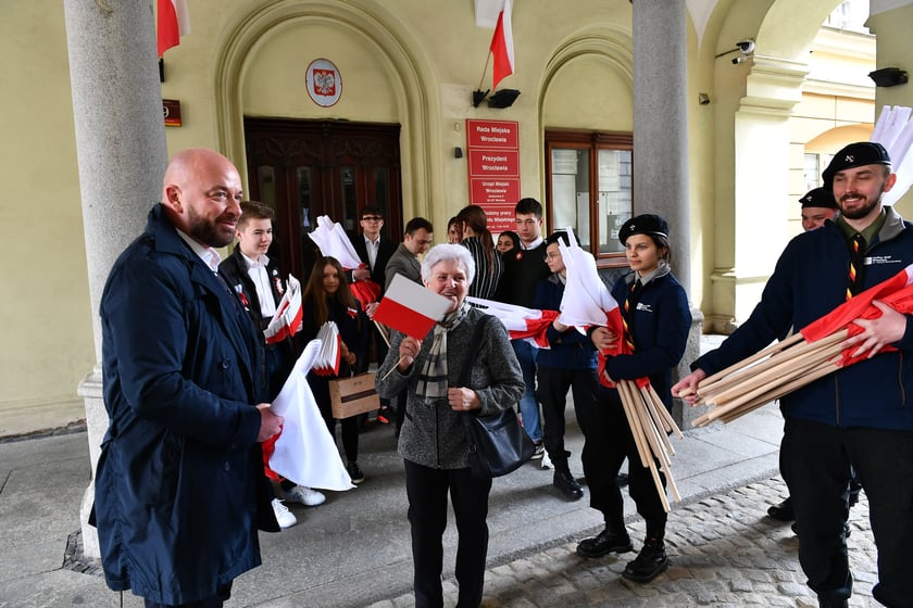 Prezydent Wrocławia Jacek Sutryk rozdaje flagi mieszkańcom i turystom.