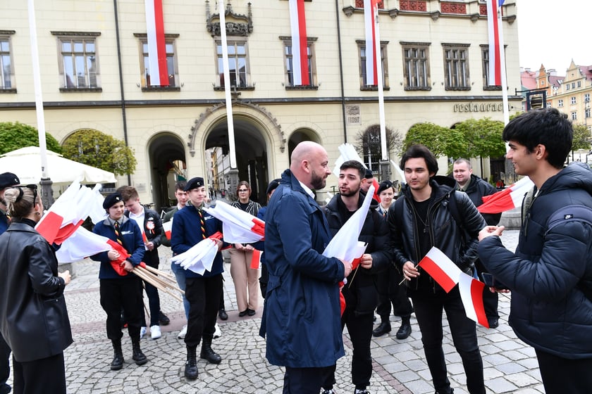Prezydent Wrocławia Jacek Sutryk rozdaje flagi mieszkańcom i turystom.