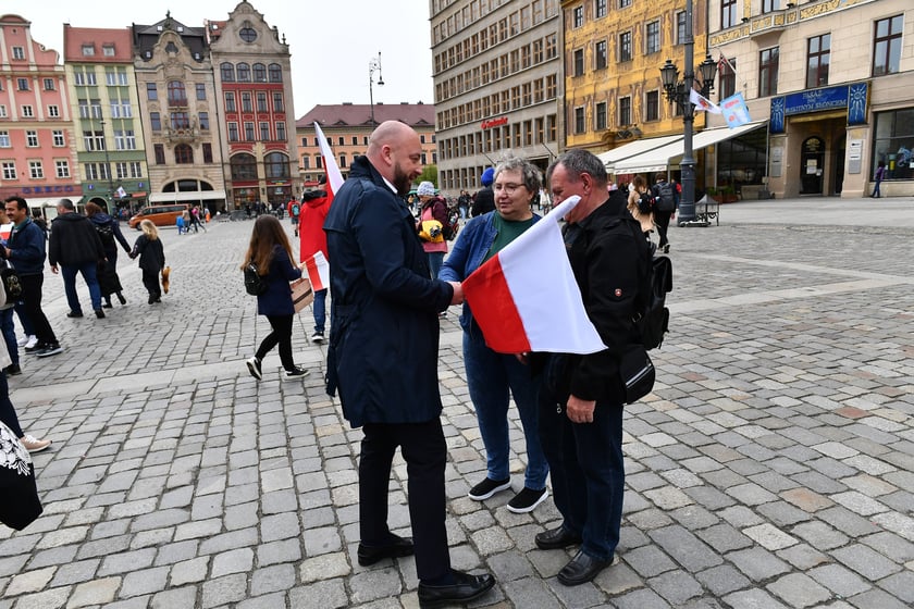 Prezydent Wrocławia Jacek Sutryk rozdaje flagi mieszkańcom i turystom.
