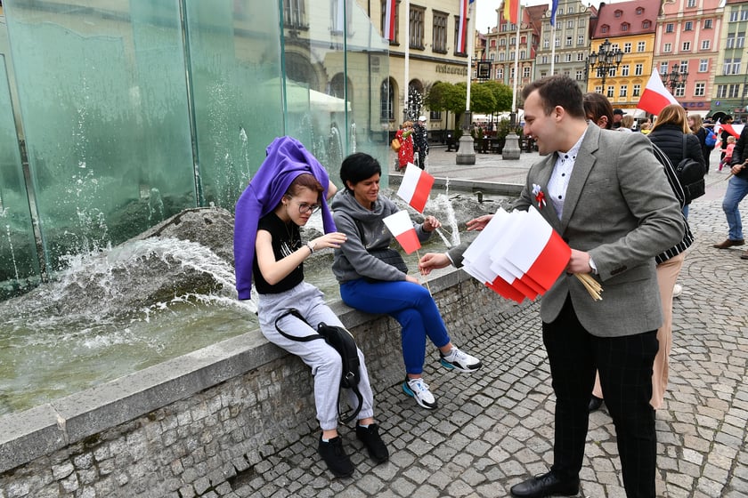 Prezydent Wrocławia Jacek Sutryk rozdaje flagi mieszkańcom i turystom.