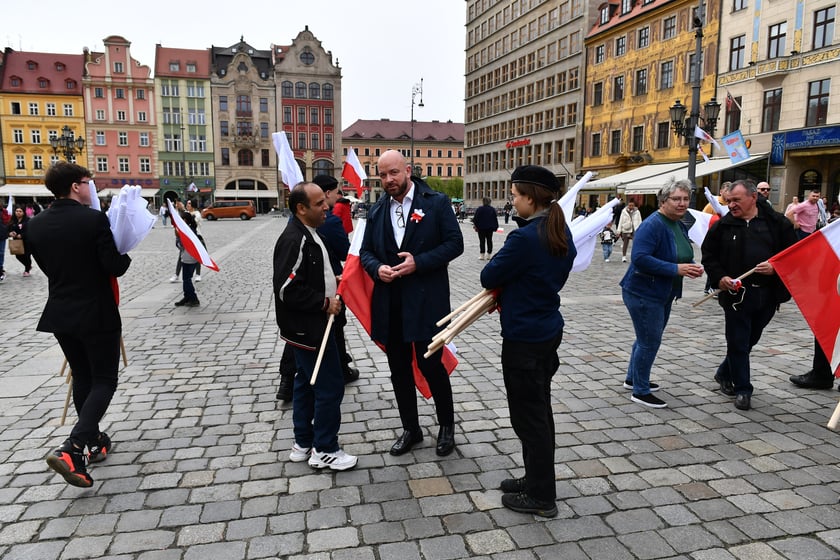 Prezydent Wrocławia Jacek Sutryk rozdaje flagi mieszkańcom i turystom.