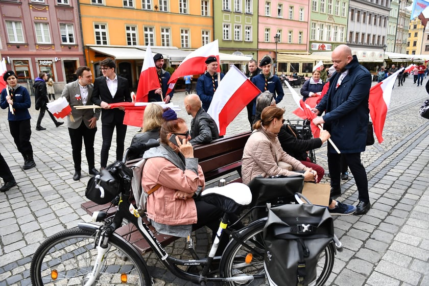 Prezydent Wrocławia Jacek Sutryk rozdaje flagi mieszkańcom i turystom.