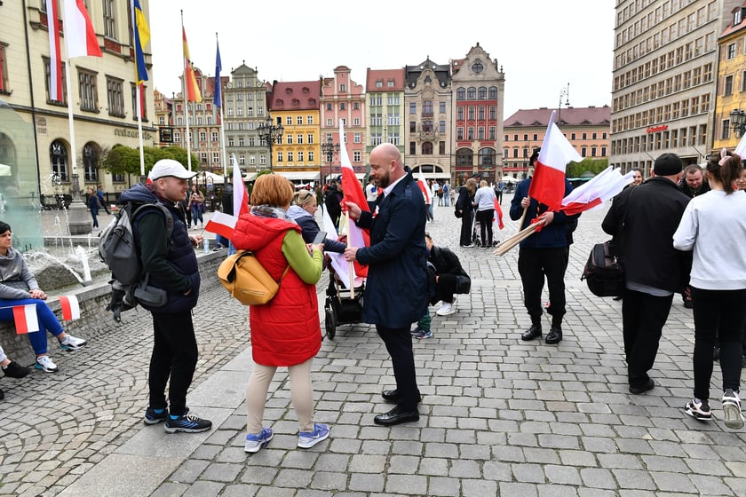 Prezydent Wrocławia Jacek Sutryk rozdaje flagi mieszkańcom i turystom.