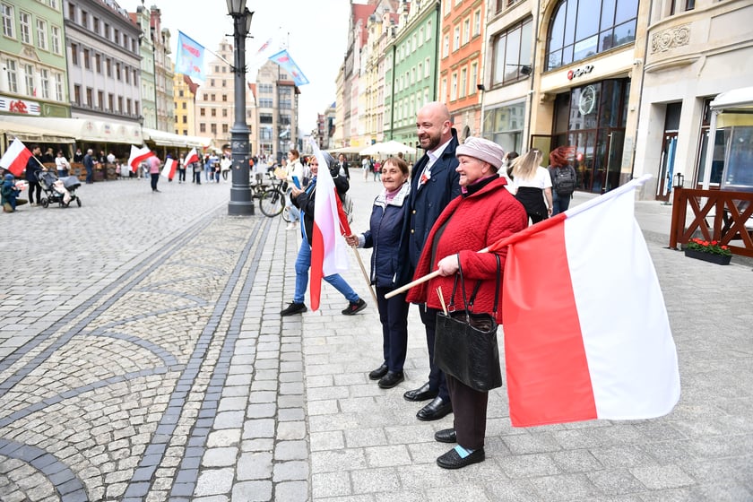 Prezydent Wrocławia Jacek Sutryk rozdaje flagi mieszkańcom i turystom.