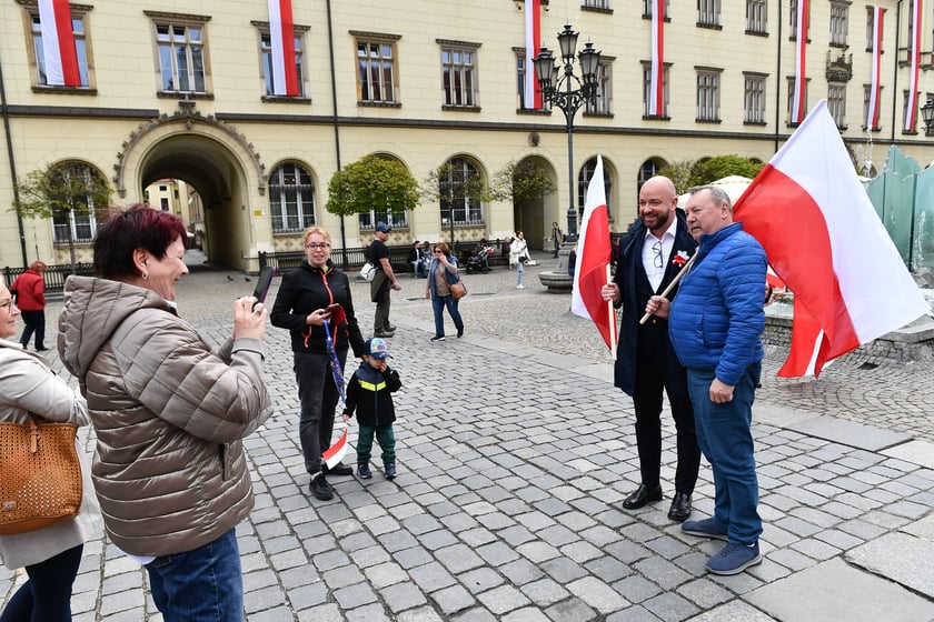 Prezydent Wrocławia Jacek Sutryk rozdaje flagi mieszkańcom i turystom.