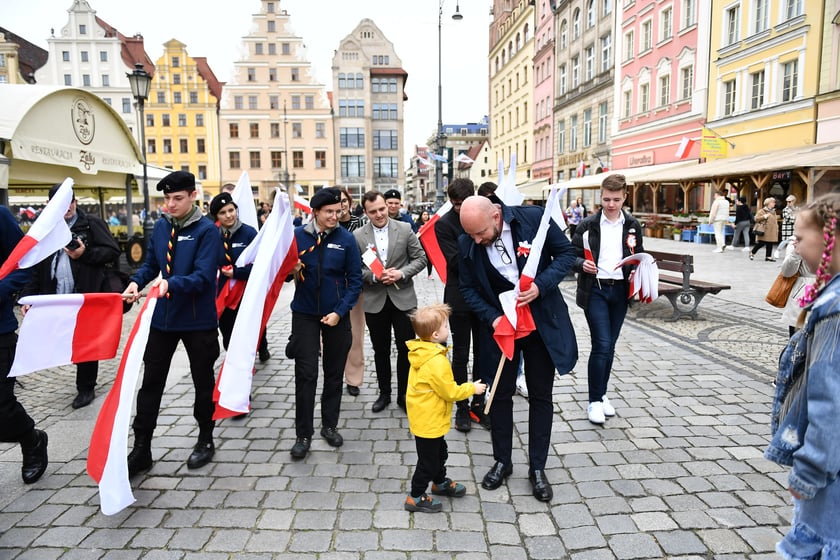 Prezydent Wrocławia Jacek Sutryk rozdaje flagi mieszkańcom i turystom.