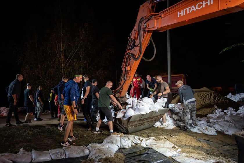 Kobiety i mężczyźni układają worki z piaskiem na Marszowicach w nocy z 17 na 18 września 2024 roku
