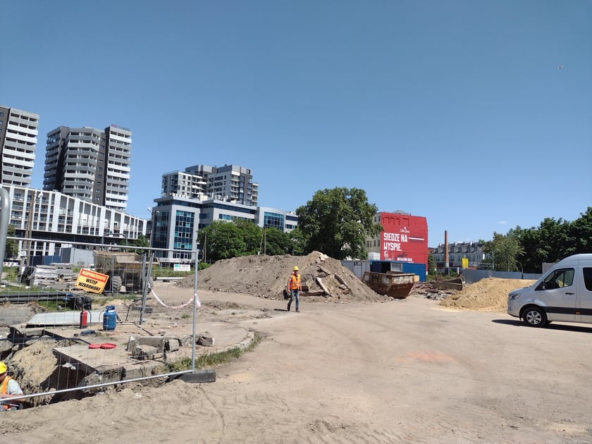 Głębokie wykopy w drodze rowerowej i plac budowy obok