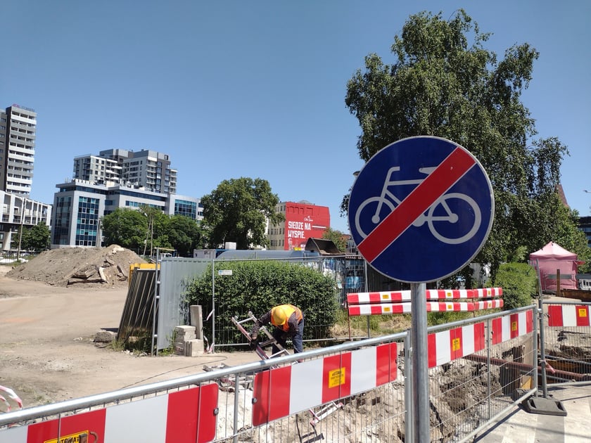 Głębokie wykopy w drodze rowerowej i plac budowy obok