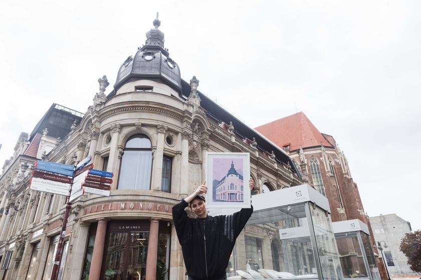 Malwa Domaradzka z plakatem, na kt&oacute;rym przedstawiła Hotel Monopol na tle prawdziwego budynku