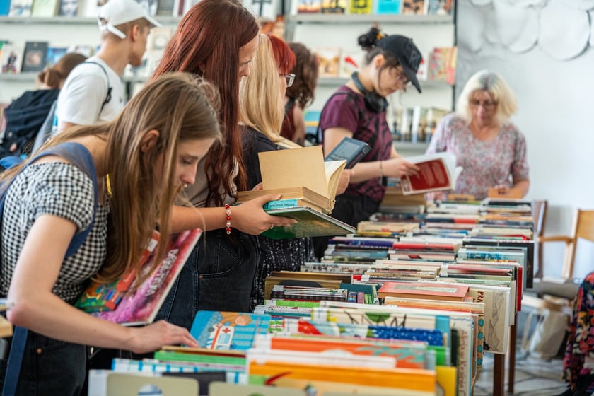 Czytelnicy przeglądający książki i inne zbiory wystawione na sprzedaż w Dolnośląskiej Bibliotece Publicznej w rynku
