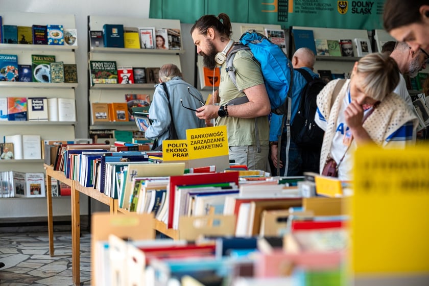 Czytelnicy przeglądający książki i inne zbiory wystawione na sprzedaż w Dolnośląskiej Bibliotece Publicznej w rynku