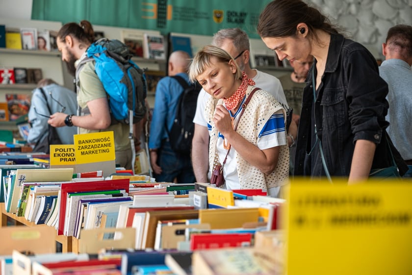 Czytelnicy przeglądający książki i inne zbiory wystawione na sprzedaż w Dolnośląskiej Bibliotece Publicznej w rynku