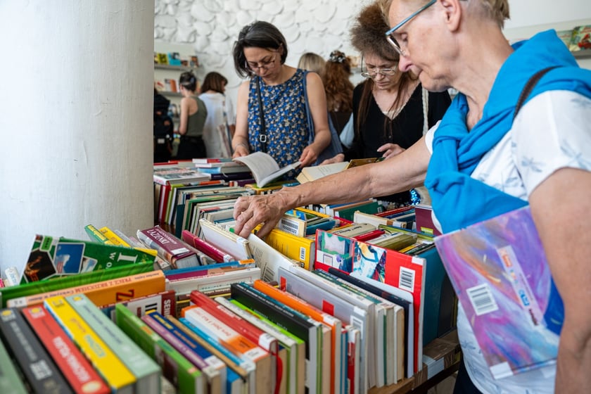 Czytelnicy przeglądający książki i inne zbiory wystawione na sprzedaż w Dolnośląskiej Bibliotece Publicznej w rynku