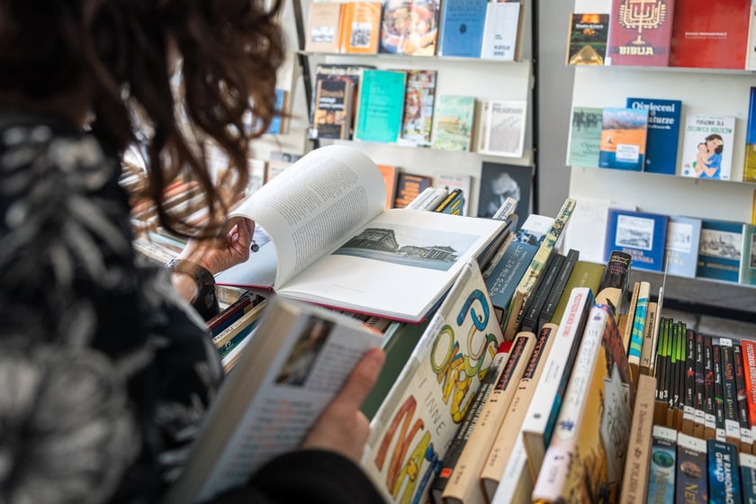Czytelnicy przeglądający książki i inne zbiory wystawione na sprzedaż w Dolnośląskiej Bibliotece Publicznej w rynku