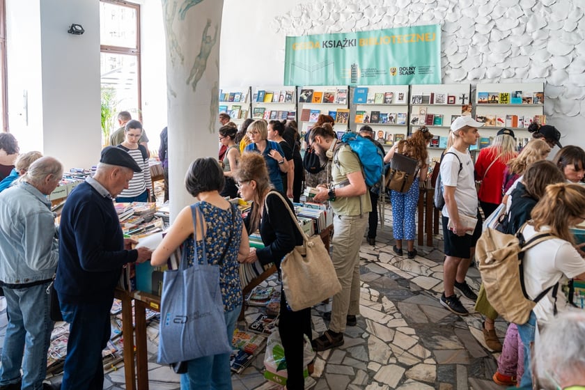 Czytelnicy przeglądający książki i inne zbiory wystawione na sprzedaż w Dolnośląskiej Bibliotece Publicznej w rynku