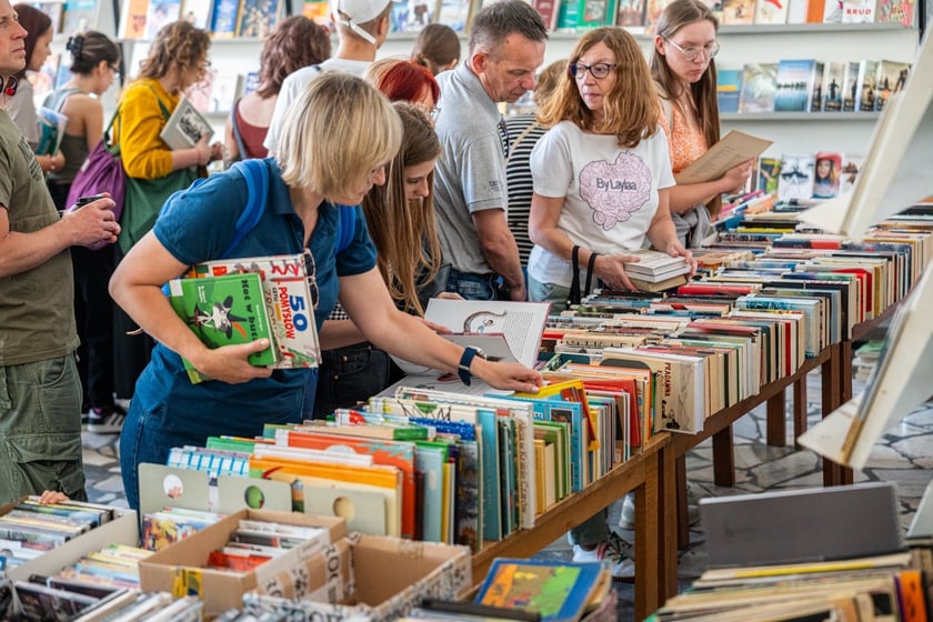 Czytelnicy przeglądający książki i inne zbiory wystawione na sprzedaż w Dolnośląskiej Bibliotece Publicznej w rynku