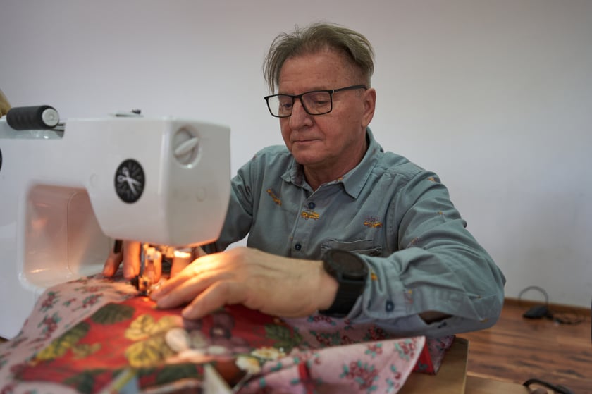 Uczestnik warsztat&oacute;w z ekokrawiectwa w trakcie szycia na maszynie