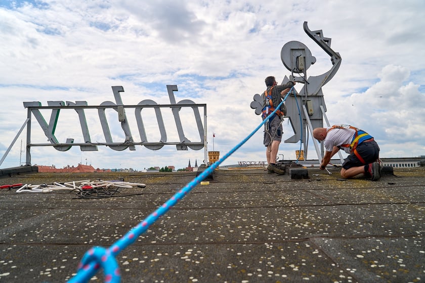 Zdejmowanie rurek z napisu i pana neonu "dobry wieczór we Wrocławiu"