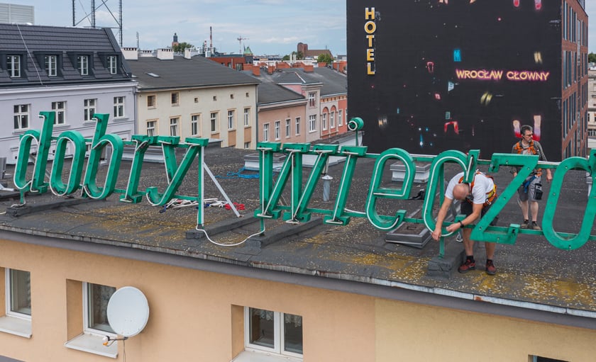 Zdejmowanie rurek z napisu i pana neonu "dobry wieczór we Wrocławiu"