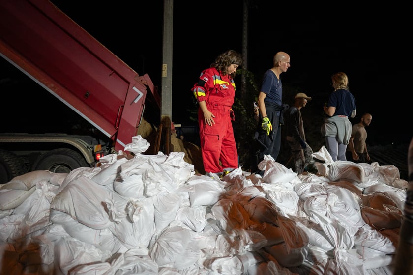 Kobiety i mężczyźni układają worki z piaskiem na Marszowicach w nocy z 17 na 18 września 2024 roku
