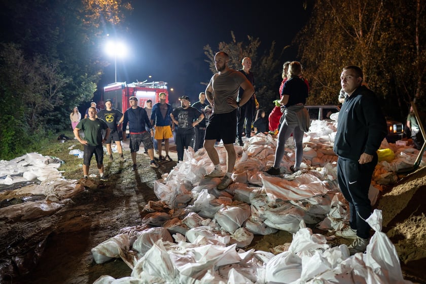 Kobiety i mężczyźni układają worki z piaskiem na Marszowicach w nocy z 17 na 18 września 2024 roku