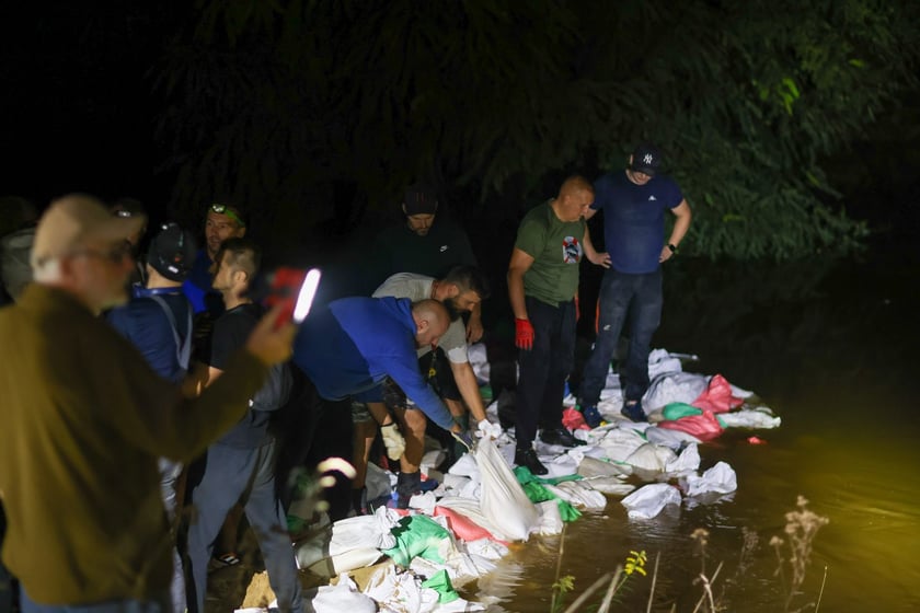 Kobiety i mężczyźni podczas akcji  na wale Janówek - Pracze. Trwa jego uszczelnianie