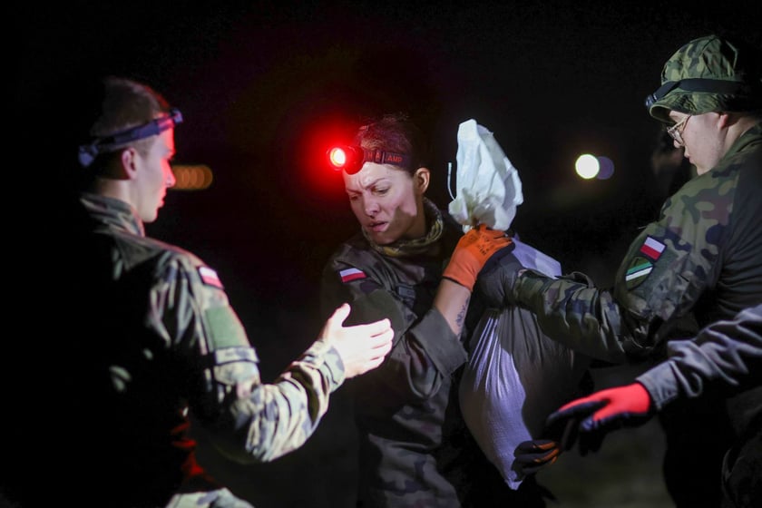 Kobiety i mężczyźni podczas akcji  na wale Janówek - Pracze. Trwa jego uszczelnianie