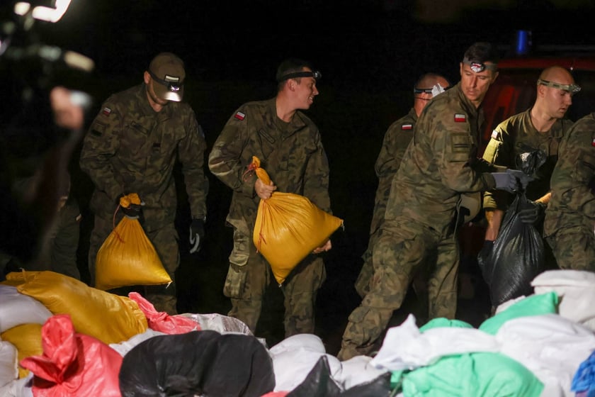 Kobiety i mężczyźni podczas akcji  na wale Janówek - Pracze. Trwa jego uszczelnianie