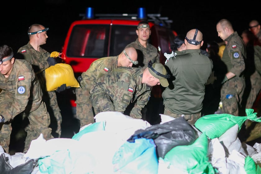 Kobiety i mężczyźni podczas akcji  na wale Janówek - Pracze. Trwa jego uszczelnianie