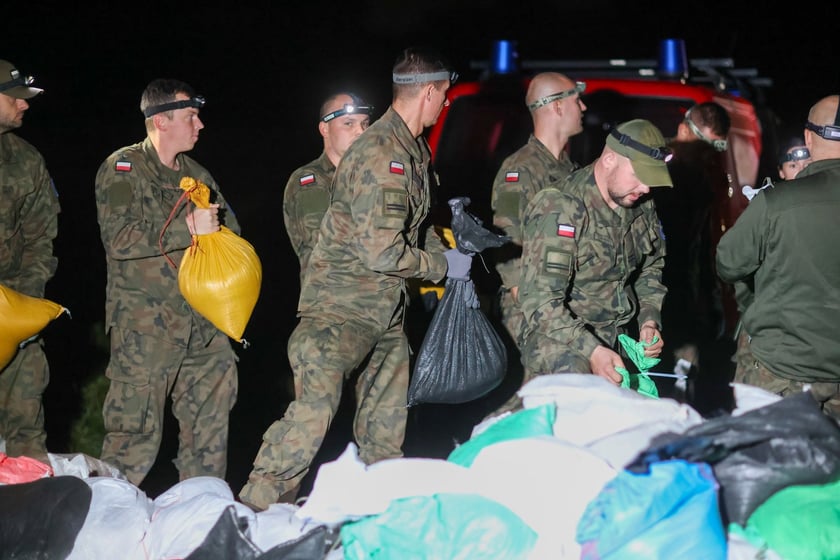 Kobiety i mężczyźni podczas akcji  na wale Janówek - Pracze. Trwa jego uszczelnianie