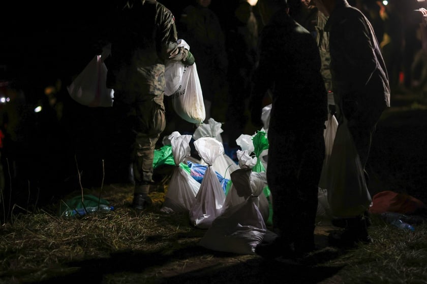 Kobiety i mężczyźni podczas akcji  na wale Janówek - Pracze. Trwa jego uszczelnianie