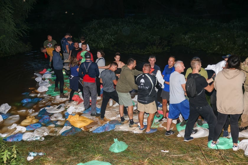 Kobiety i mężczyźni podczas akcji  na wale Janówek - Pracze. Trwa jego uszczelnianie