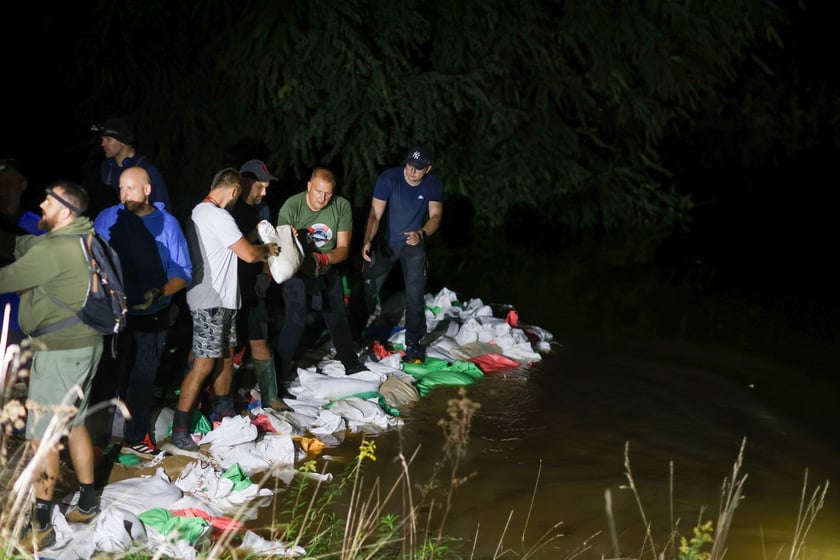 Kobiety i mężczyźni podczas akcji  na wale Janówek - Pracze. Trwa jego uszczelnianie
