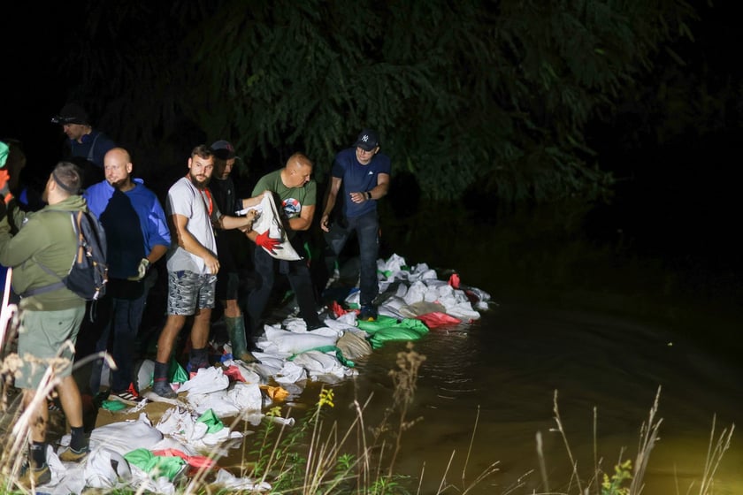 Kobiety i mężczyźni podczas akcji  na wale Janówek - Pracze. Trwa jego uszczelnianie
