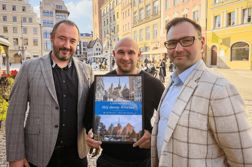 Trzech mężczyzn: w środku Łukasz Stelmach, po lewej stronie Mariusz Kotkowski, prawej Tomasz Sielicki współwłaściciele Wydawnictwa Wrocławski Neptun.