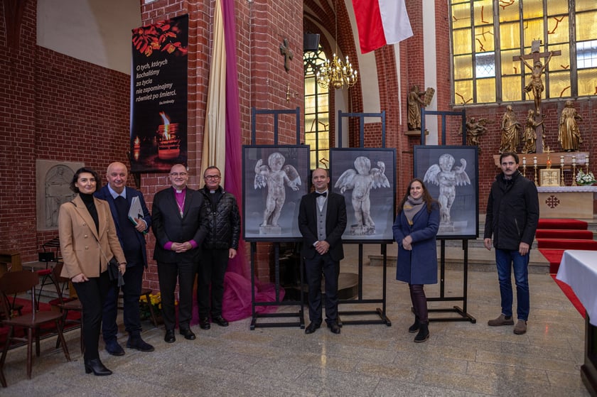Osoby zaangażowane w proces powrotu figurek anielskich do kościoła św. Marii Magdaleny na tle zdjęć aniołk&oacute;w