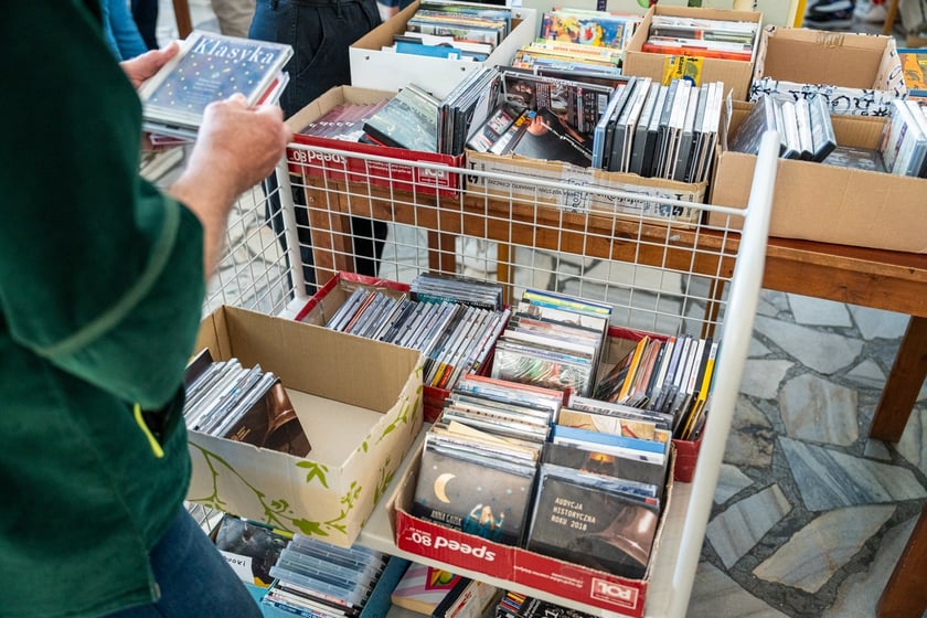 Czytelnicy przeglądający książki i inne zbiory wystawione na sprzedaż w Dolnośląskiej Bibliotece Publicznej w rynku