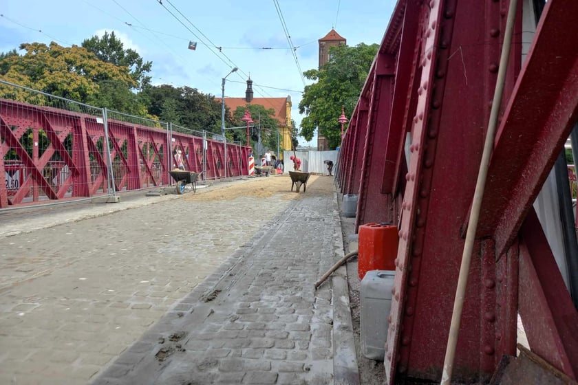 Kostka na moście jest już zaspoinowana. Trwa piaskowanie.