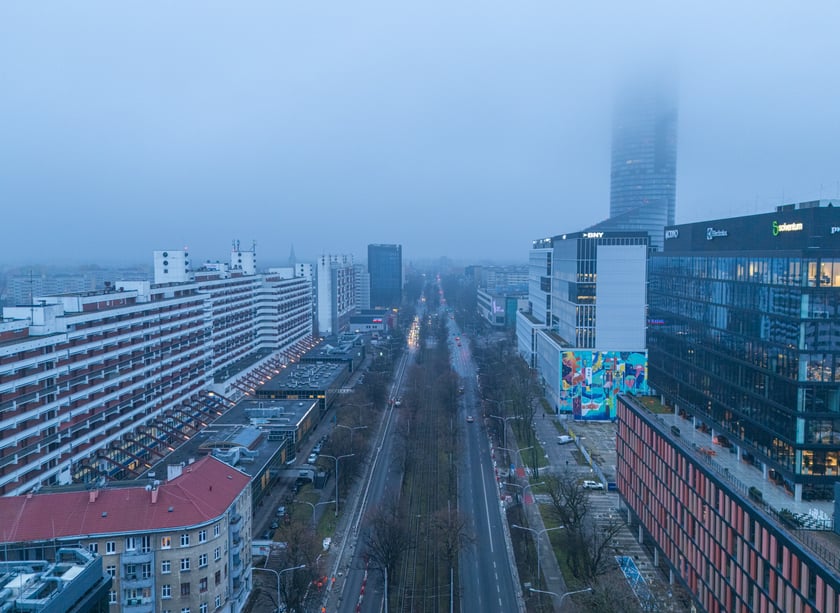 Powiększ obraz: Widok z lotu ptaka na dwujezdniową ulicę, z torowiskiem tramwajowym po środku i budynki stojące przy niej. Wyremontowany fragment ul. Powstańców Śląskich.