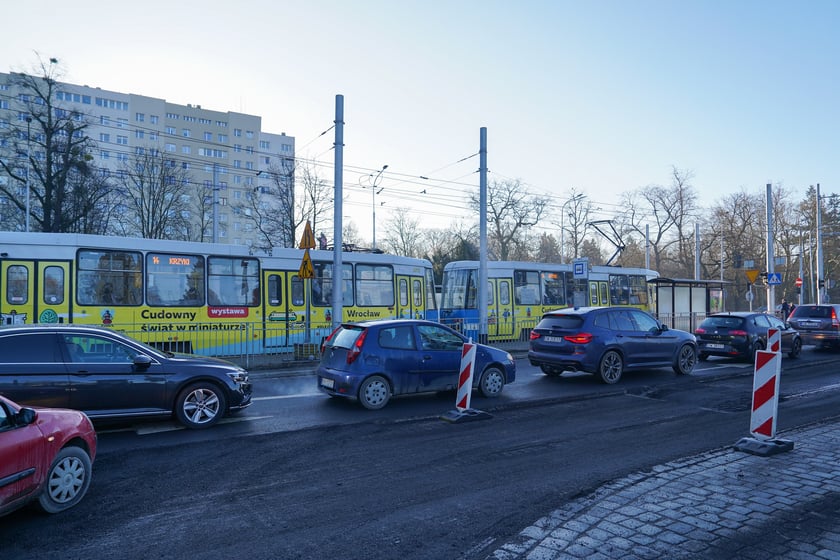 Powiększ obraz: Jezdnia ze sfrezowanym asfaltem na jednym pasie i auta jadące po drugim - remontowany fragment ul. Powstańców Śląskich.