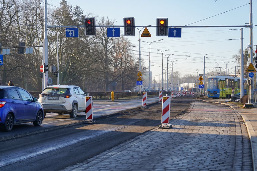 Powiększ obraz: Jezdnia ze sfrezowanym asfaltem na jednym pasie i auta jadące po drugim - remontowany fragment ul. Powstańców Śląskich.