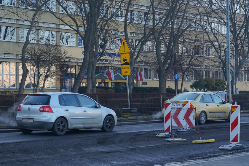 Powiększ obraz: Jezdnia ze sfrezowanym asfaltem na jednym pasie i auta jadące po drugim - remontowany fragment ul. Powstańców Śląskich.