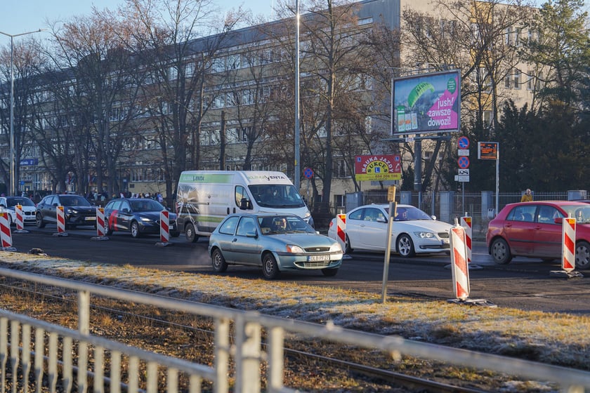 Powiększ obraz: Jezdnia ze sfrezowanym asfaltem na jednym pasie i auta jadące po drugim - remontowany fragment ul. Powstańców Śląskich.