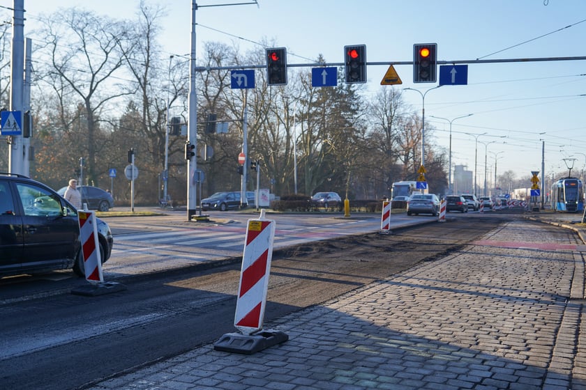 Powiększ obraz: Jezdnia ze sfrezowanym asfaltem na jednym pasie i auta jadące po drugim - remontowany fragment ul. Powstańców Śląskich.