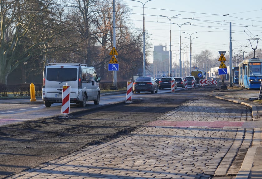 Powiększ obraz: Jezdnia ze sfrezowanym asfaltem na jednym pasie i auta jadące po drugim - remontowany fragment ul. Powstańców Śląskich.