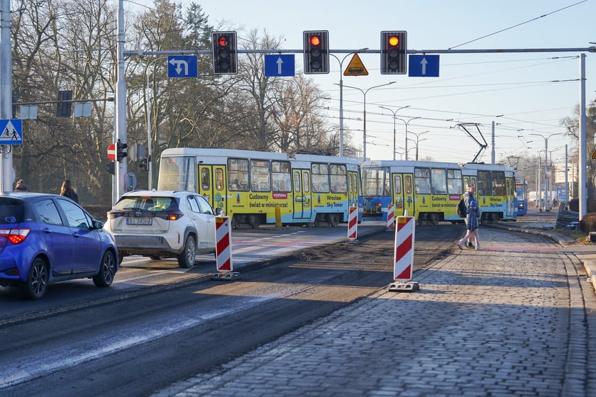 Powiększ obraz: Jezdnia ze sfrezowanym asfaltem na jednym pasie i auta jadące po drugim - remontowany fragment ul. Powstańców Śląskich.