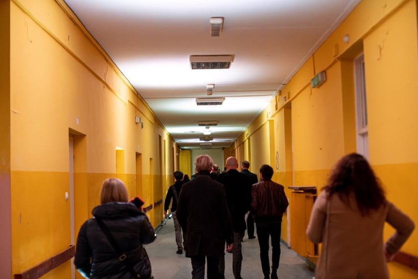 Słuchacze podążający za dźwiękiem po  korytarzach dawnego szpitala